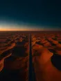 Dawn aerial photograph: one empty road running through orange dunes toward the sunrise horizon.
