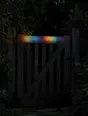 Refracted-light photograph: a closed garden gate at dusk, refracted light running along its top rail.