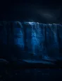 Dark elemental photograph: a layered glacial ice wall glowing deep blue, its newest top rim dissolving into small glowing marks.