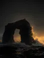 Dark elemental photograph: a half carved black sea arch at golden hour, its unfinished side dissolving into warm glowing marks.