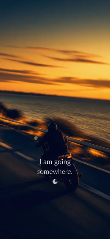 Affirmations for men wallpaper: panned photograph of a man riding a motorcycle away up an empty coast road at golden hour, the roadside pulled sideways by the movement and the sea opening out beyond, with the affirmation 'I am going somewhere.' in serif type.