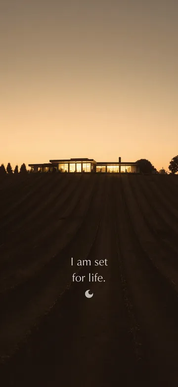 Struck-light photograph: a hillside of vine rows at dusk below one low lit house on the ridge, with the typeset line "I am set for life."