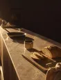 Struck-light photograph: a stone kitchen counter at dawn with breakfast half made along it, bread part cut on a board, a pan and a cup set out