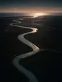 Dawn aerial photograph: a river winding across a dark plain toward the sea at first light.