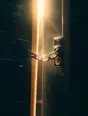 Prism-light photograph: A door chain drawn across a narrow gap in a door, dust drifting in the lit air of the gap.
