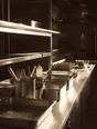 Struck-light photograph: the steel pass of a professional kitchen in the morning, wiped down and squared off before service
