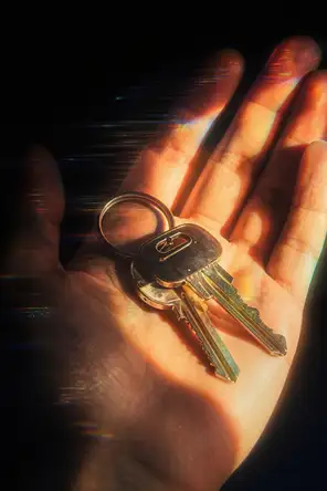 Prism-light photograph: A set of keys resting in an open palm, hard sun across the skin and the cut metal.