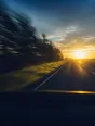 Motion photograph: an empty road running out ahead from inside a moving car at dawn, the verge tearing past and the sky opening at the far end