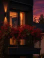 Film photograph: a balcony window box overflowing with deep red flowers, lit warm at dusk against a dark facade.