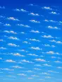 Grainy gradient illustration: A morning sky crowded with small scattered clouds in restless rows, bright blue behind them.