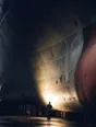 Dark cinematic photograph: One person standing tiny at the foot of an enormous ship's hull in dry dock, floodlights raking up the steel plating.
