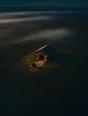 Dawn aerial photograph: a barn at first light with doors open and a cart already out, mist beyond.
