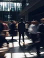 Motion photograph: a man in a suit standing completely still in a bright high atrium at midday while the crowd crossing around him blurs