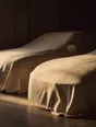 Struck-light photograph: two cars under fitted covers of unbleached canvas in a private garage, low light raking the weave