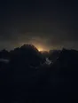 Dark elemental photograph: a jagged ridge before sunrise, pale gold light gathering behind the summit and dissolving into small glowing marks.