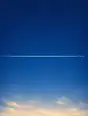 Grainy gradient illustration: A single arrow-straight white jet trail crossing a clear deep blue morning sky.