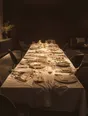Struck-light photograph: a long dining table after a dinner, glasses and plates still standing, chairs pushed back at angles