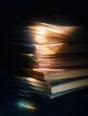 Prism-light photograph: A stack of well-thumbed notebooks with their page edges fanned and combed by hard sun.