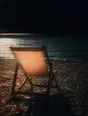 Prism-light photograph: One deckchair open and facing the sea on an empty shingle beach at late sun.