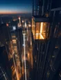 Motion photograph: a glass lift climbing the outside of a tall building at dusk, the whole city dropping away beneath it