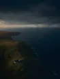 Dawn aerial photograph: a rain squall moving out to sea beyond a headland, a drystone sheepfold in first gold.