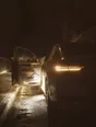 Struck-light photograph: a car left at the kerb at night with its headlights on and the driver's door standing open