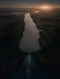 Dawn aerial photograph: a canal sluice just opened at dawn, ripples spreading down the still water.