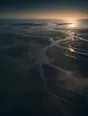 Dawn aerial photograph: silver ebb-tide channels braiding across dark mudflats past a small wooden jetty.