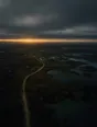 Dawn aerial photograph: a raised stone causeway crossing wet moorland under heavy low cloud.
