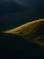 Dawn aerial photograph: the line of first gold light moving down a mountainside toward a small hay barn.