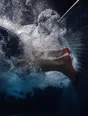 Motion photograph: a swimmer's turn at the wall of a pool, the push-off churn filling the frame and the feet just leaving the tiles