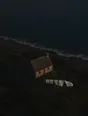 Dawn aerial photograph: white sheets on a washing line in a stiff breeze beside a lone stone cottage by the sea.