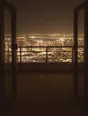 Struck-light photograph: a terrace high above a lit city at night with the doors standing open behind it