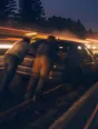 Motion photograph: two men pushing a broken-down car along a road at dusk, leaning into it with their weight