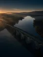 Dawn aerial photograph: an old many-arched stone bridge crossing a misty river at sunrise.