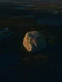 Dawn aerial photograph: one colossal glacial boulder resting alone on a dark heath plain.
