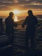 Dark cinematic photograph: Exactly two people pulling off their gloves as they meet at a field gate, silhouetted against low sun.