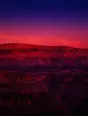 Film photograph: layered canyon rock glowing red and violet at dusk, each stratum banded in crisp shadow.