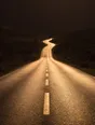 Struck-light photograph: a long empty coast road late in the afternoon with nothing on it and nothing coming the other way