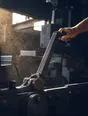 Motion photograph: a heavy machine lever hauled over mid-travel in a workshop, its linkage swinging