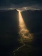 Dawn aerial photograph: the rising sun breaking through a notch in a dark ridge, one beam entering the valley.