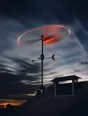 Motion photograph: a weather vane spinning hard on a roof against a fast-moving sky at dusk