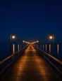 Film photograph: a long pier reaching into calm dark water at night, every lamp lit along its length.