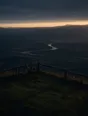 Dawn aerial photograph: a bicycle leaning on a wooden viewpoint rail above a sunrise valley, no rider in sight.