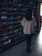 Dark cinematic photograph: A wall of school pigeonholes every one of them full, one person's back walking past it.
