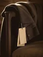 Struck-light photograph: a good coat left over the arm of a chair with its tags still hanging from the sleeve