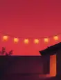 Grainy gradient illustration: A string of paper lanterns lit warm across a courtyard as the sky behind goes deep rose.