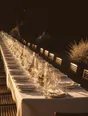 Struck-light photograph: a long table being laid for many at dusk, the terrace beyond it already in shadow