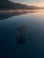 Dawn aerial photograph: an old wooden diving platform standing over a glass-still dark lake.