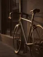 Struck-light photograph: a bicycle leaned against a wall in low afternoon light outside a shop that has shut early